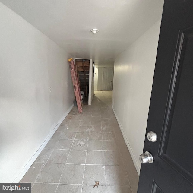 hallway with light tile patterned flooring and baseboards