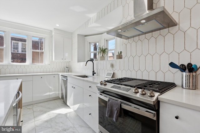 kitchen featuring range hood, a sink, stainless steel appliances, white cabinets, and marble finish floor