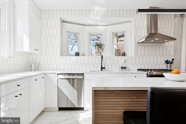 kitchen featuring dishwasher, white cabinetry, wall chimney range hood, and a sink