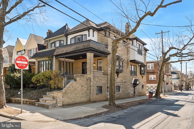 view of front of property featuring brick siding, a residential view, and a chimney