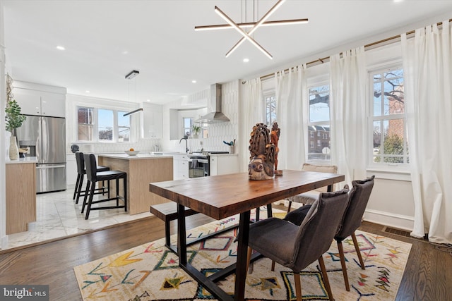 dining space with recessed lighting, baseboards, light wood-type flooring, and an inviting chandelier