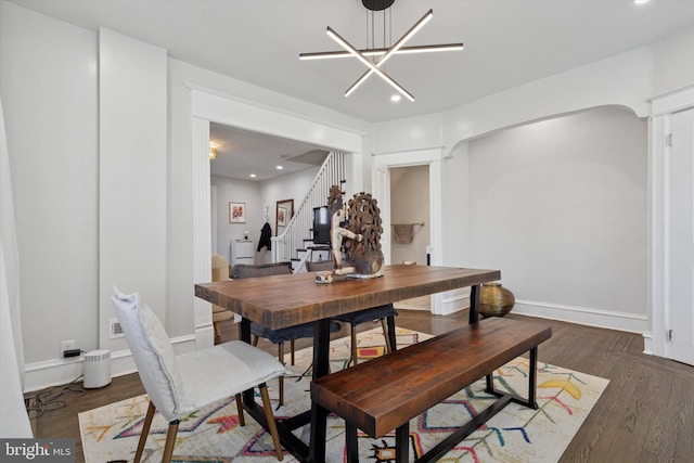 dining area featuring wood finished floors, baseboards, recessed lighting, stairs, and a notable chandelier