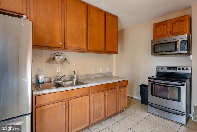 kitchen with light countertops, light tile patterned floors, appliances with stainless steel finishes, brown cabinetry, and a sink