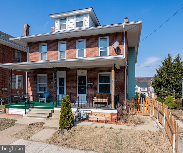 american foursquare style home with a porch, fence, and brick siding