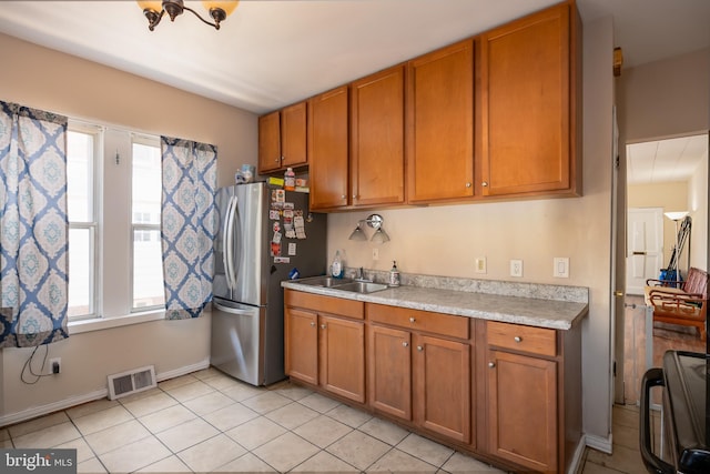 kitchen with a sink, light countertops, visible vents, and brown cabinets