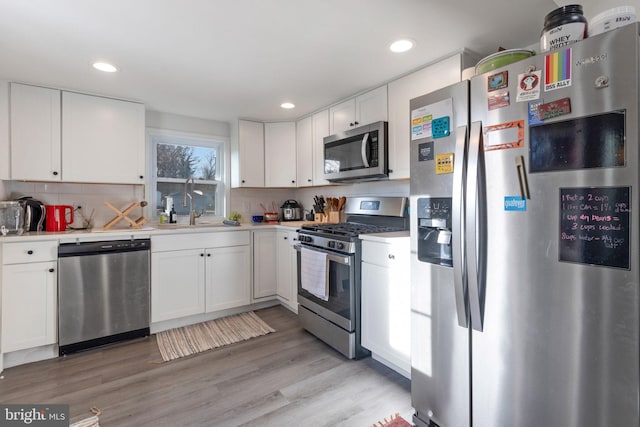 kitchen with light wood-style flooring, a sink, stainless steel appliances, light countertops, and white cabinets