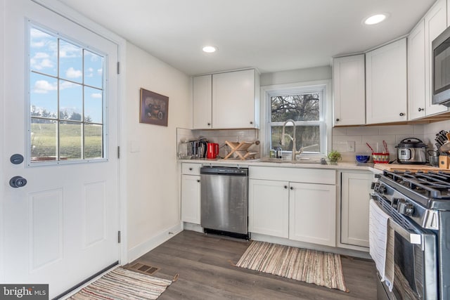 kitchen with a sink, dark wood finished floors, stainless steel appliances, white cabinets, and light countertops