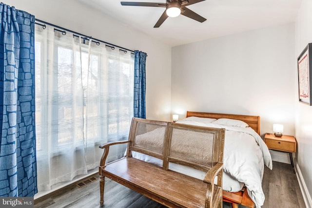 bedroom featuring visible vents, multiple windows, a ceiling fan, and wood finished floors