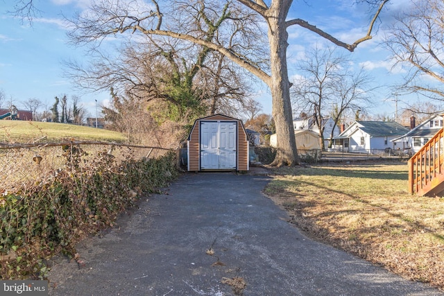 view of gate featuring an outbuilding, a storage unit, fence, and a yard