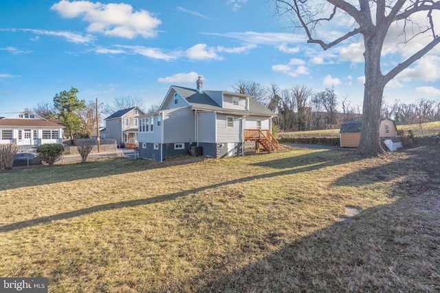 back of property with a storage shed, an outdoor structure, and a yard