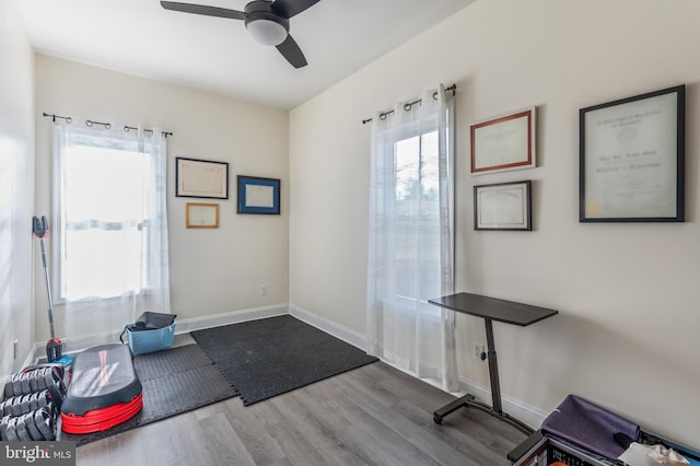 interior space with baseboards, wood finished floors, and ceiling fan