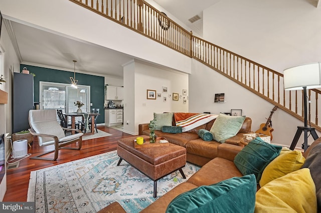 living area featuring ornamental molding, wood finished floors, stairway, a high ceiling, and baseboards