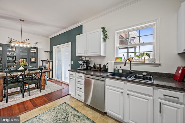 kitchen featuring a sink, dark countertops, stainless steel dishwasher, white cabinetry, and an inviting chandelier