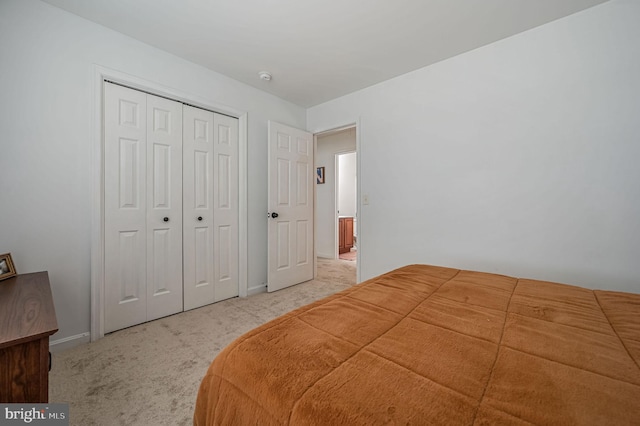 bedroom featuring a closet, baseboards, and light colored carpet