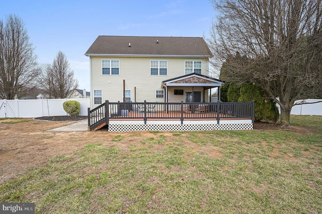 rear view of house featuring a fenced backyard, a lawn, and a wooden deck