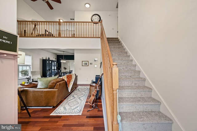 stairs featuring baseboards, wood finished floors, a towering ceiling, and a ceiling fan