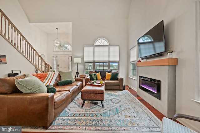 living area featuring a glass covered fireplace, a high ceiling, wood finished floors, and stairs