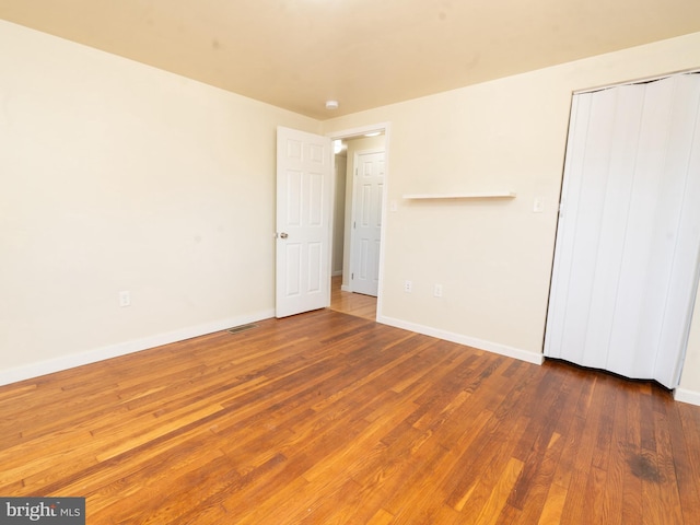 unfurnished bedroom with visible vents, baseboards, a closet, and wood finished floors