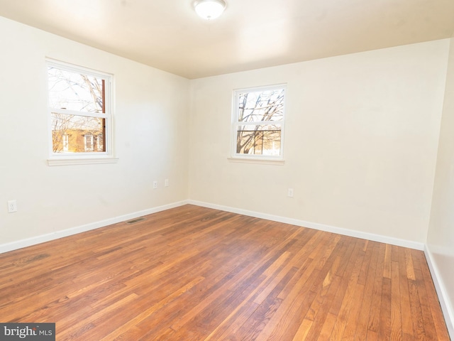 empty room with visible vents, baseboards, and hardwood / wood-style floors