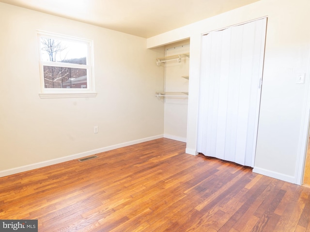 unfurnished bedroom featuring wood finished floors, visible vents, and baseboards