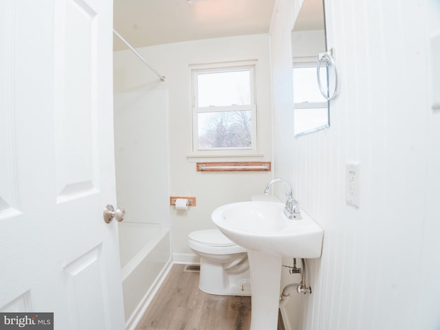 bathroom featuring visible vents, toilet, wood finished floors, baseboards, and bathing tub / shower combination