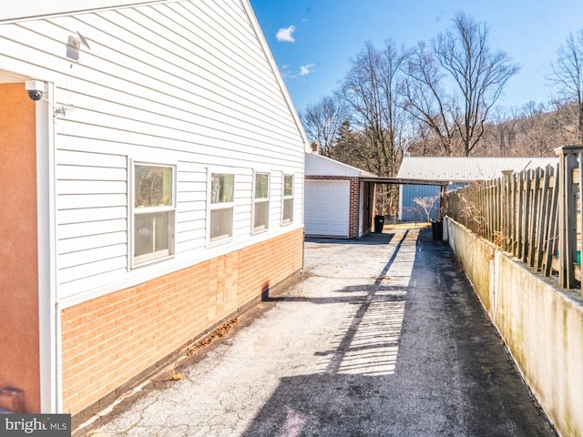 view of side of property with an outbuilding, fence, and brick siding