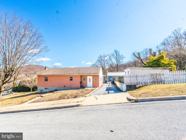 ranch-style home featuring concrete driveway, a fenced front yard, and crawl space