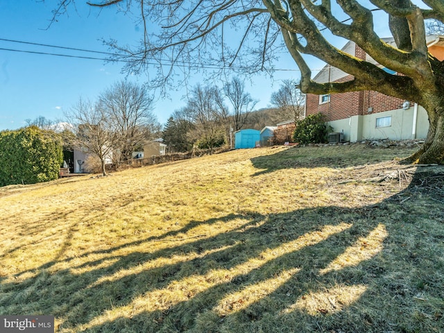 view of yard featuring an outbuilding, a shed, and central AC unit