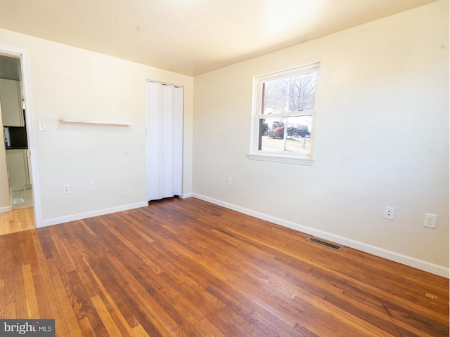 unfurnished bedroom with visible vents, baseboards, and wood finished floors