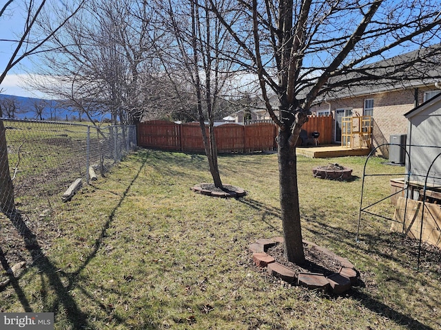 view of yard with central air condition unit, a fire pit, and a fenced backyard