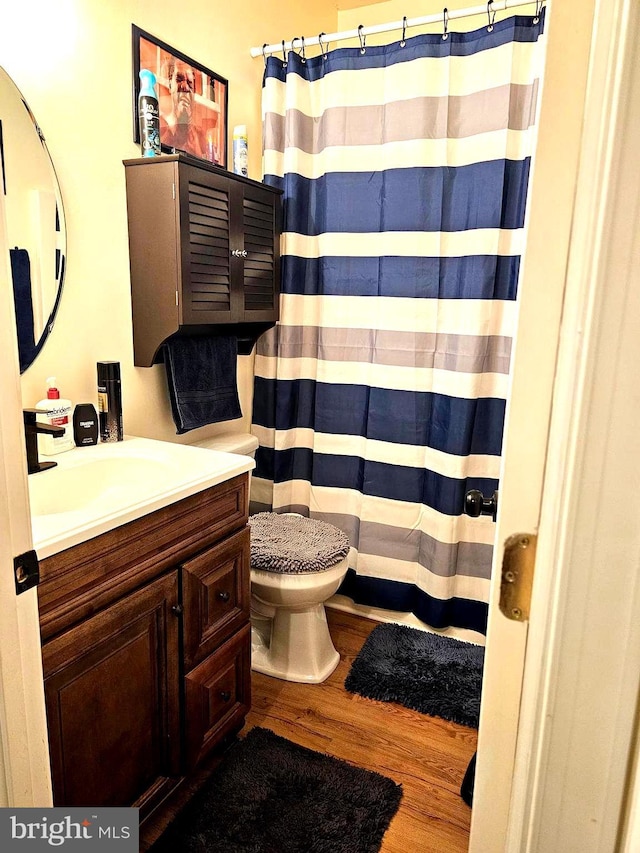 full bath featuring toilet, vanity, a shower with curtain, and wood finished floors