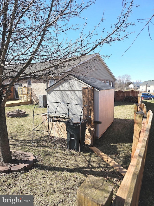 view of shed featuring central AC unit, fence, and a fire pit