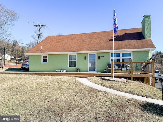 back of property with a wooden deck, brick siding, roof with shingles, and a chimney