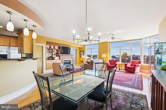 1400 Lancaster St Unit 605, Baltimore, MD 21231 - dining space with baseboards, wood finished floors, a glass covered fireplace, and ceiling fan with notable chandelier