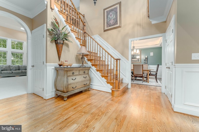 1052 Cedar Mill Ln, West Chester, PA 19382 - staircase featuring ornamental molding, wood finished floors, a decorative wall, a chandelier, and arched walkways