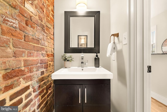 bathroom with brick wall, wood finished floors, and vanity