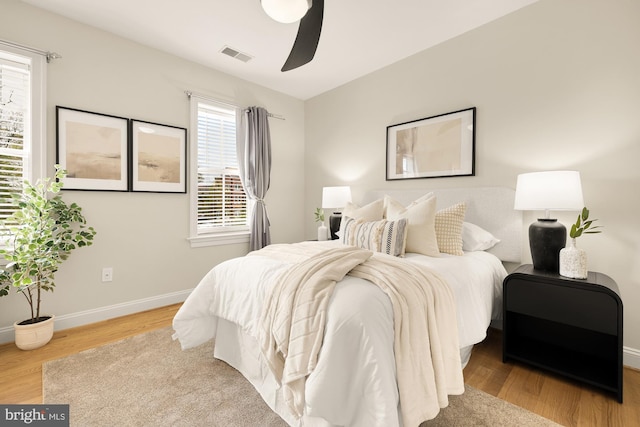 bedroom with ceiling fan, baseboards, wood finished floors, and visible vents