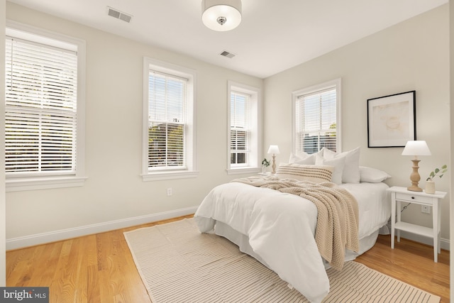 bedroom featuring wood finished floors, visible vents, and baseboards