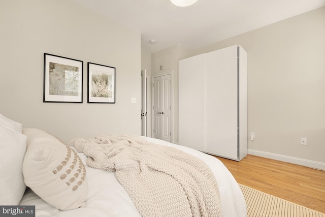 bedroom featuring baseboards, light wood finished floors, and a closet