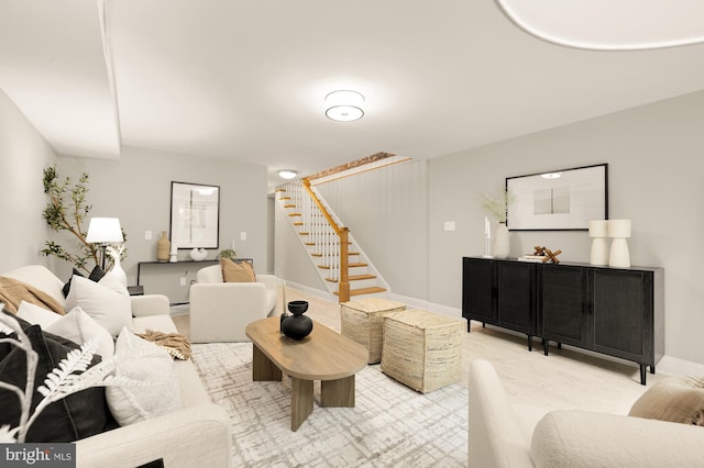 living area featuring baseboards and stairway