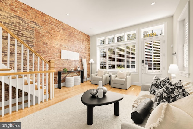 living area featuring stairway, brick wall, wood finished floors, and recessed lighting