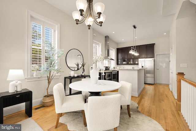 dining space featuring recessed lighting, a notable chandelier, and light wood-style flooring