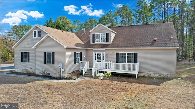 view of front of home with a deck and roof with shingles