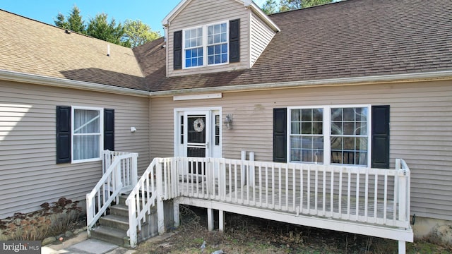 view of exterior entry featuring a shingled roof