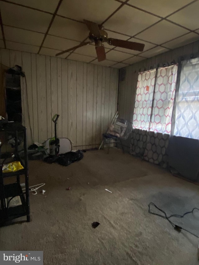 miscellaneous room with a paneled ceiling, wooden walls, and carpet floors