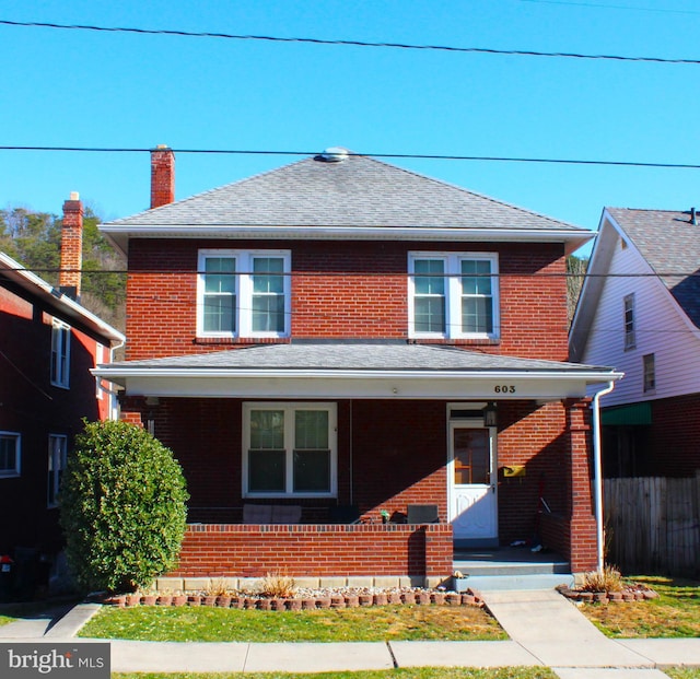 american foursquare style home featuring a porch, brick siding, and a shingled roof