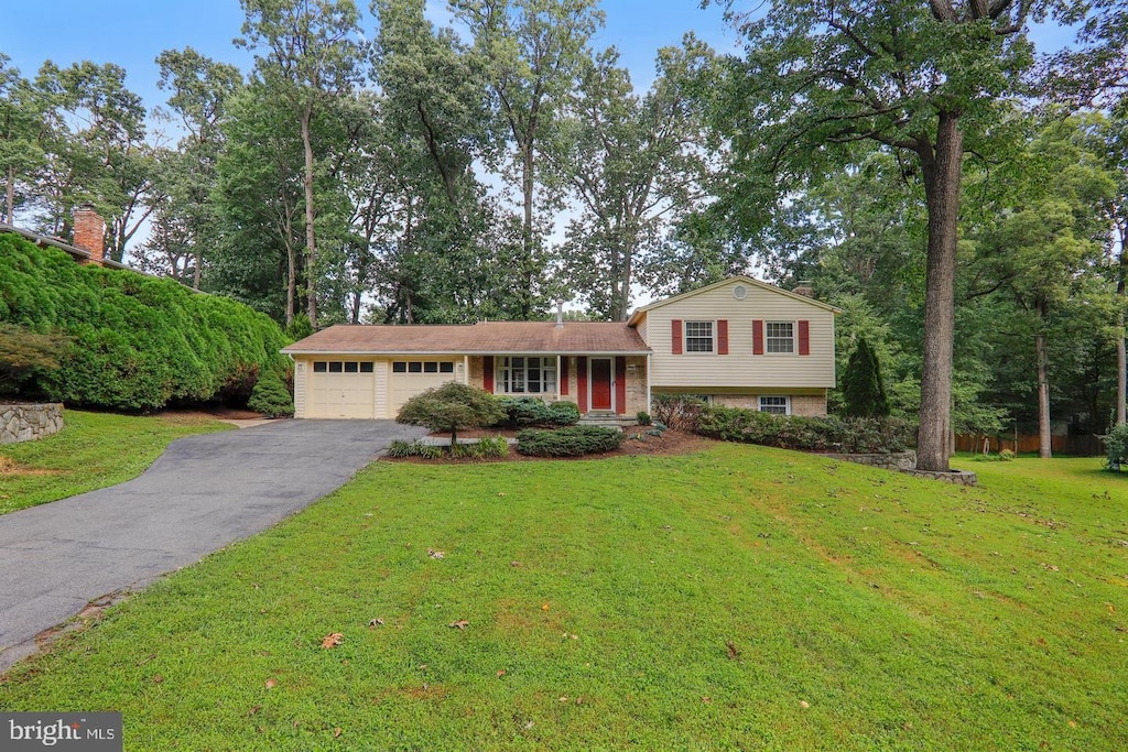 tri-level home featuring aphalt driveway, an attached garage, and a front lawn