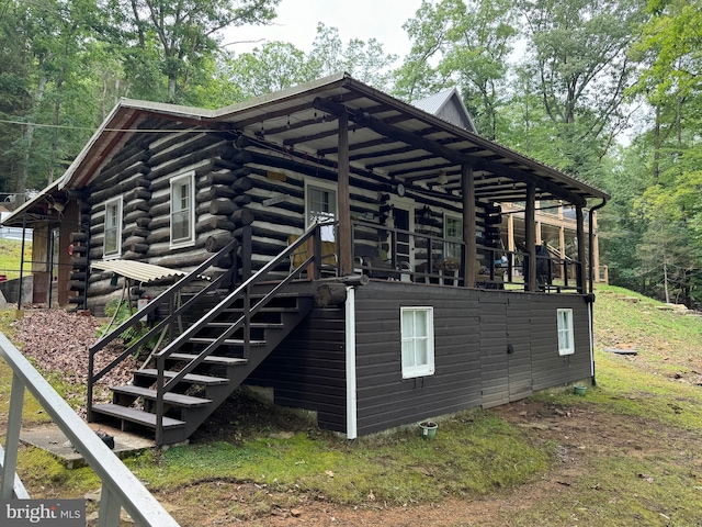 view of property exterior featuring log siding, metal roof, and stairs