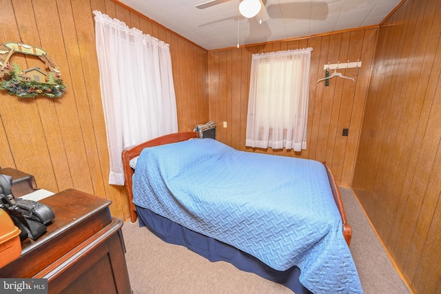 bedroom featuring carpet floors, wooden walls, and a ceiling fan