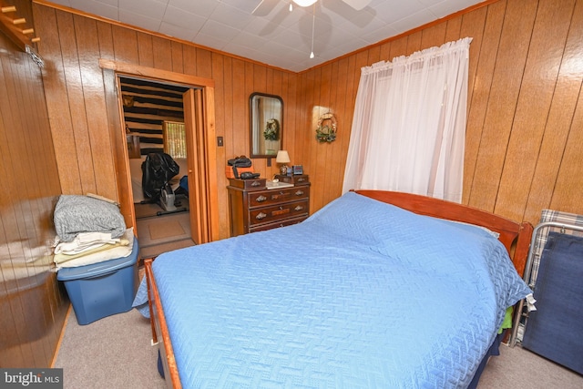 carpeted bedroom featuring a ceiling fan, a closet, and wood walls